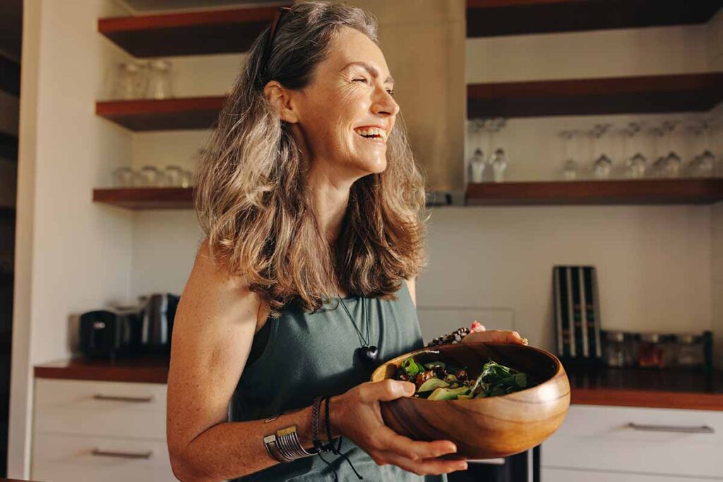 Smiling woman making a salad to get nutrients for brain health and live a healthy lifestyle
