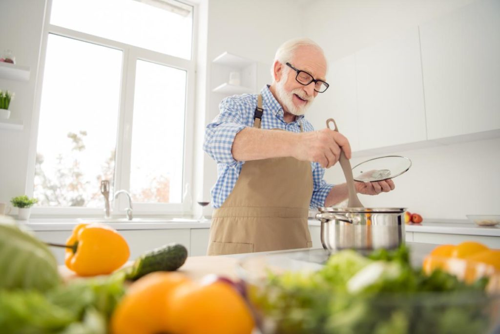 man cooking while considering his feeling about assisted living