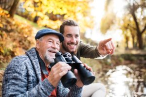 older man with binculars and son enjoying fall activities for seniors