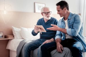 dad and son on couch talking about memory care for seniors