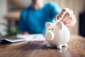 senior puts money in piggy bank while saving for retirement