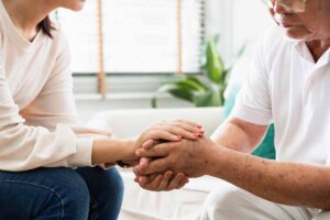 Caregiver and senior joining hands and supporting one another during mental health awareness month