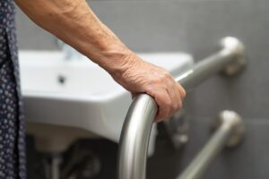 Older person in bathroom holding grab bar and therefore reducing fall risk