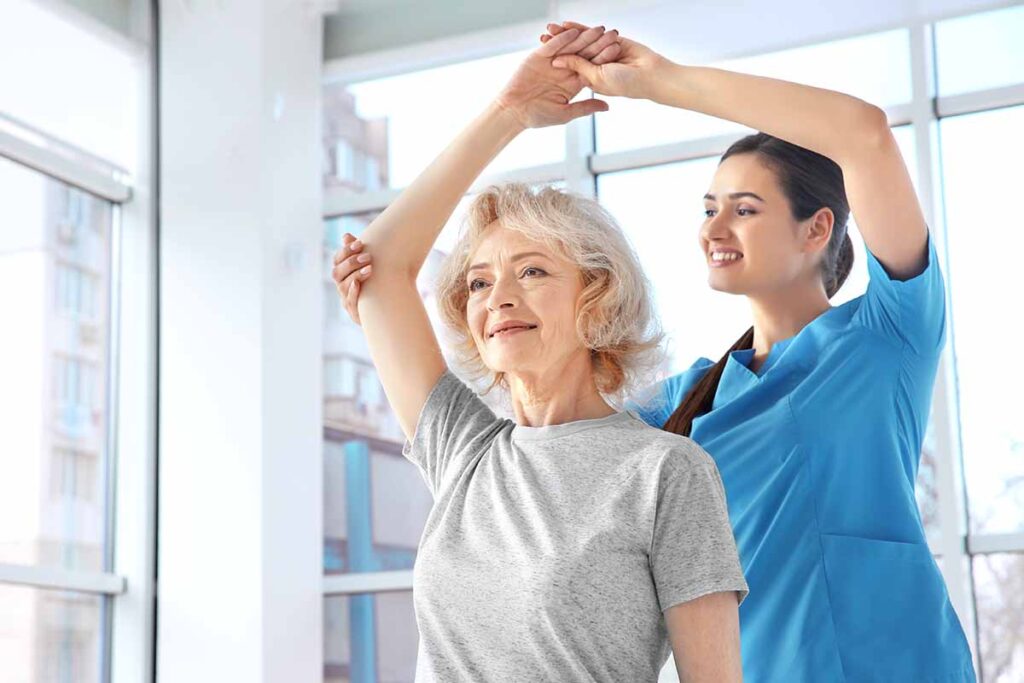 Caregiver guiding older woman through stretches as one of many ways for preventing osteoporosis