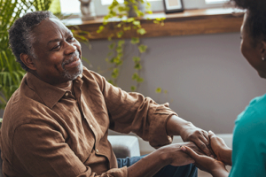 Man smiling while talking to a caregiver in an assisted living community