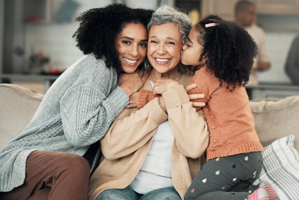 Senior woman being embraced by daughter and granddaughter while in memory care for seniors in dallas fort worth