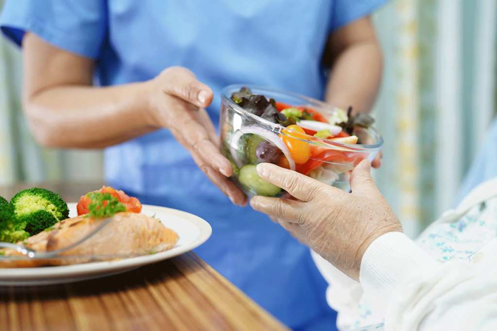 Caregiver handing woman a healthy salad which is food to boost your immune system