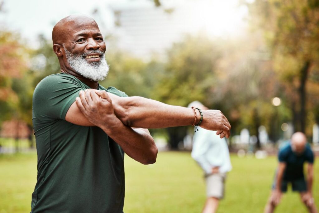 Senior man smiling while stretching outdoors demonstrating how being outside can help memory