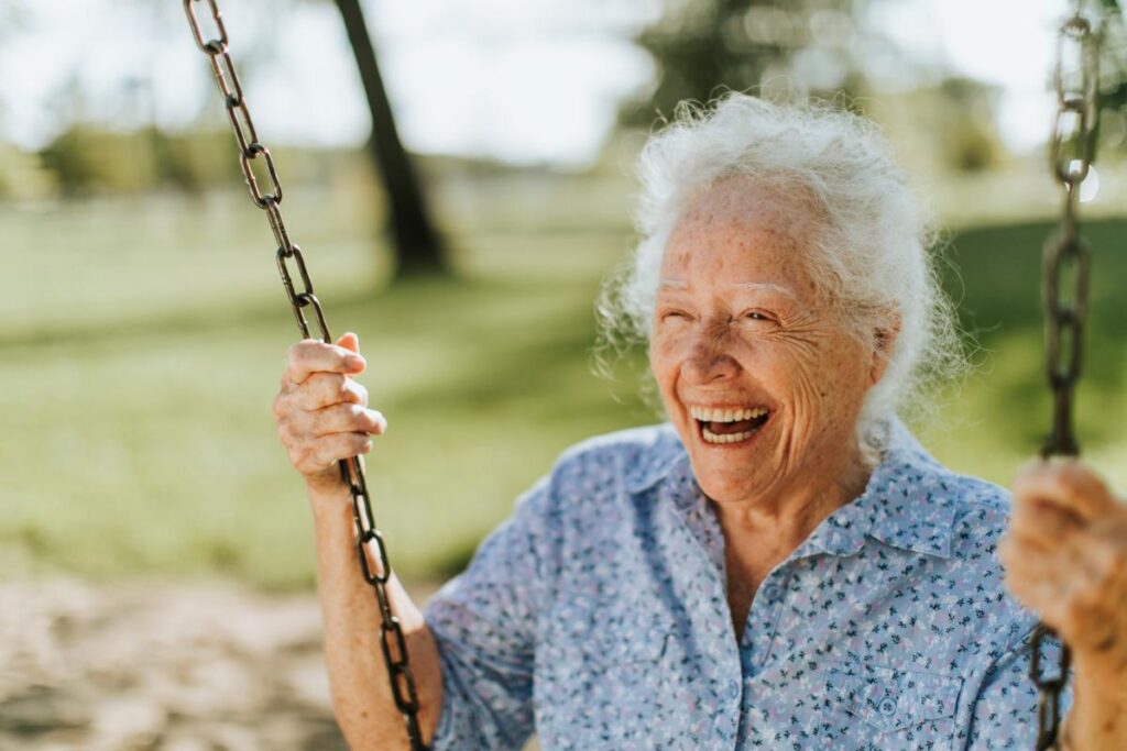 Smiling and laughing senior woman on a swing wondering when is assisted living not appropriate