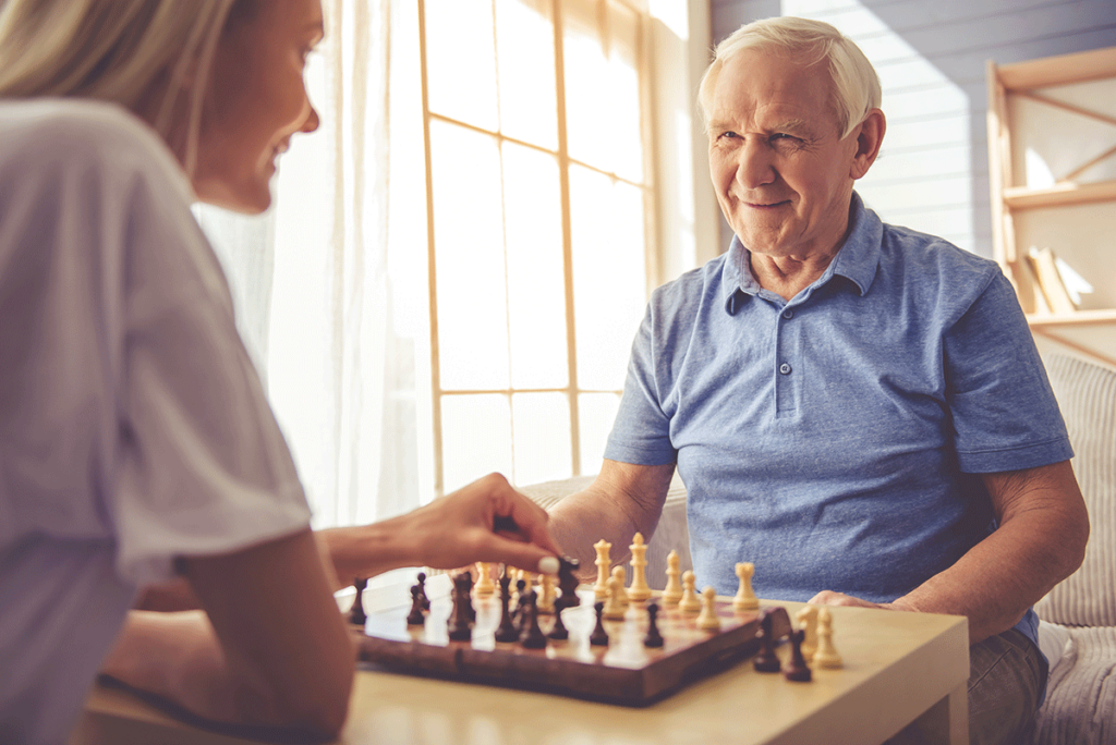 Happy man playing chess with loved one reaping the benefits of how memory care communities offer support to families
