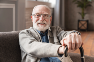 Man smiling while sitting on comfortable couch while receiving senior living services in texas