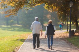 Two seniors taking a walk in the park on a pleasant sunny day as a way of prioritizing active senior living