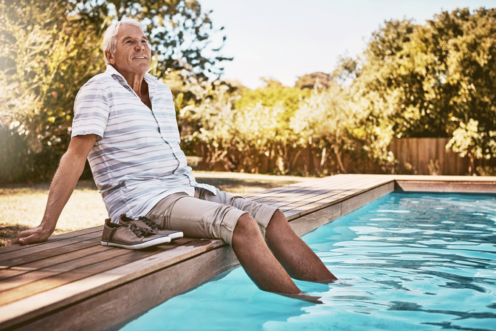 Man relaxing on a sunny day with his feet in a swimming pool while enjoying summer activities for seniors