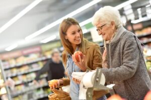 Young person and older adult shopping at the grocery store for healthy foods after learning the importance of nutrition for seniors