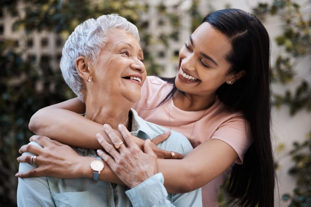 Older woman and caretaker smiling and embracing after finding assisted living in dallas