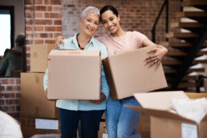 senior mother and daughter holding boxes during the process of downsizing elderly parents