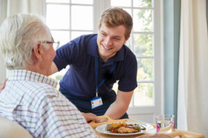 caretaker providing senior with delicious meal after discussing answers to what is long term skilled nursing care