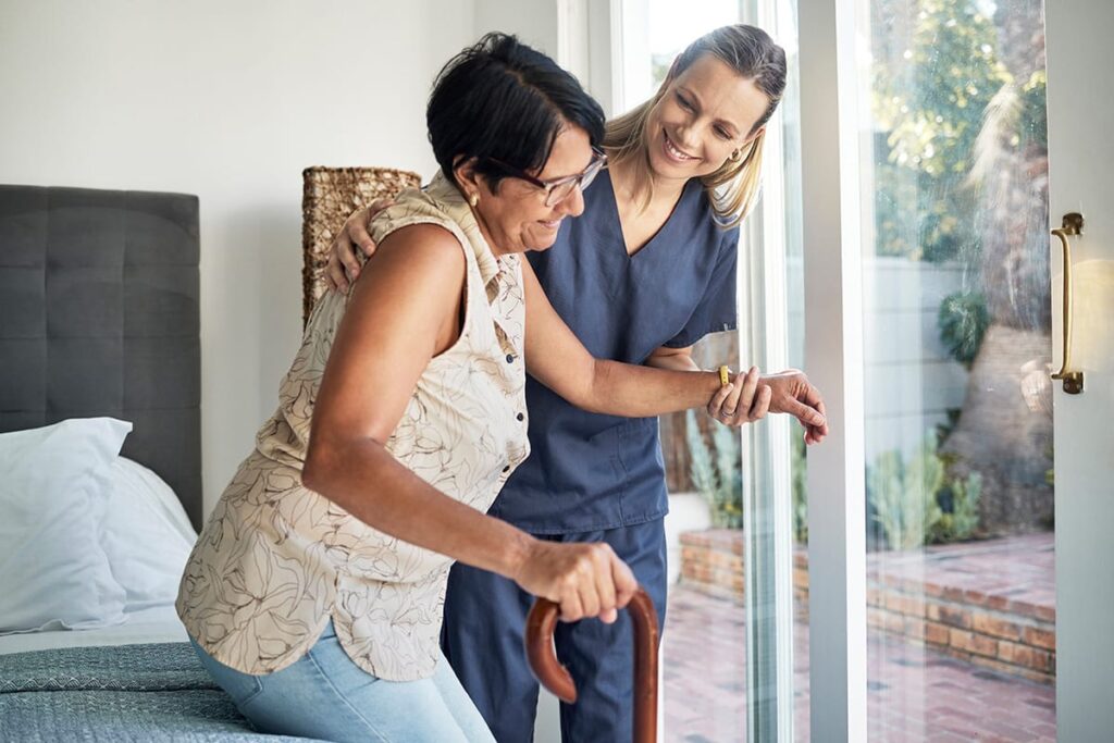 caregiver helping woman walk onto patio while discussing answers to the question what is short term rehab