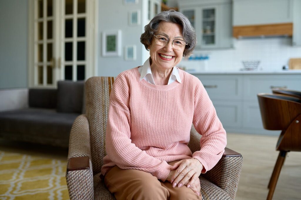smiling woman sitting on comfortable chair while reaping short-term rehab benefits